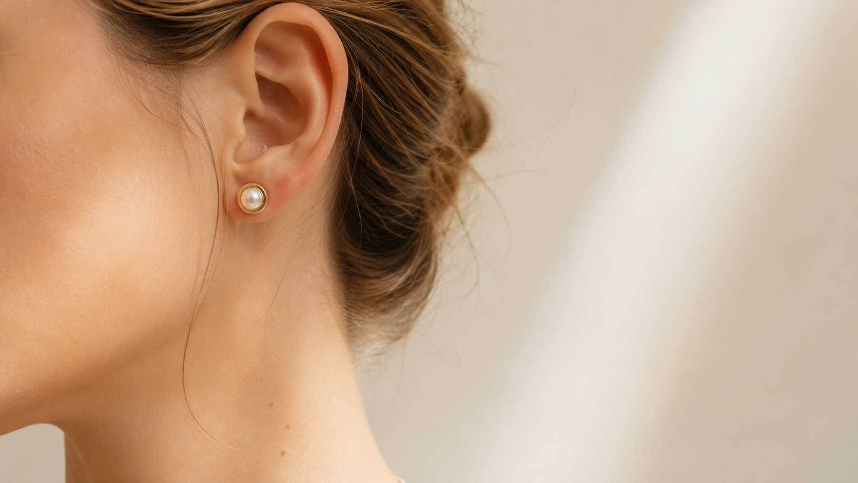 The Half Pearl stud worn close to the ear in soft window light.